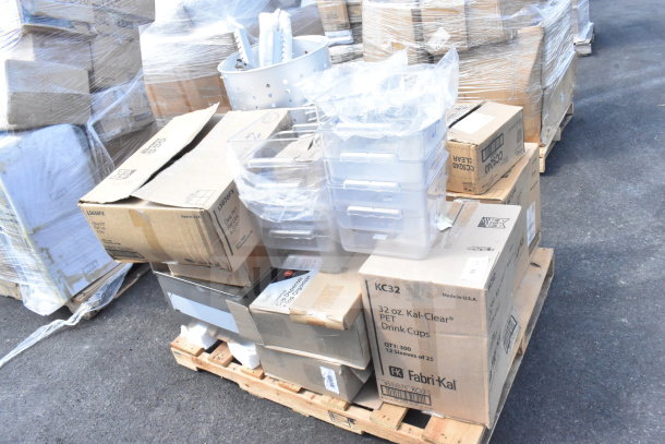 Stack of boxes and items on a pallet including tumblers, drainboards, and lids, labeled with various brand markings.