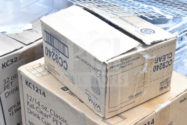 Cardboard boxes labeled "12/14 oz. Classic Kal-Clear PET Drink Cups" and "C9240 Clear Tumblers" are stacked, showing packaging details.