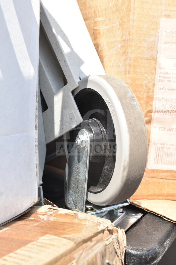Close-up of a caster wheel with 6x1 1/4 markings, attached to a metal base, surrounded by cardboard packaging.