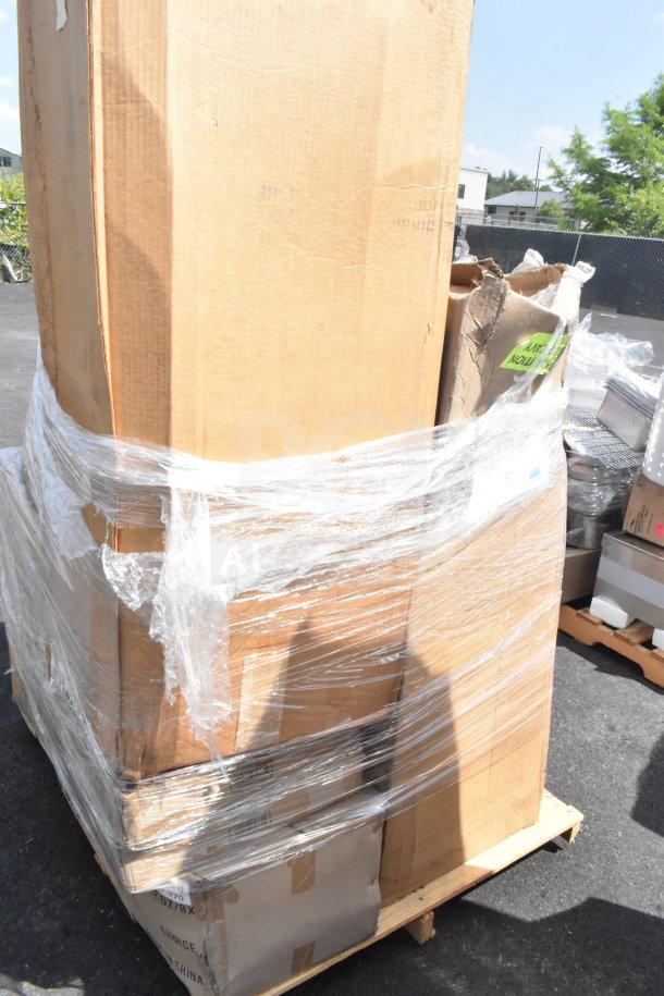 Pallet with 13 new scratch and dent items, including a table base column, wrapped in plastic and cardboard boxes.