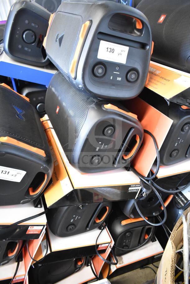 Stack of JBL speakers on display, each with orange accents and control panels. Labels indicate "QTY x4."