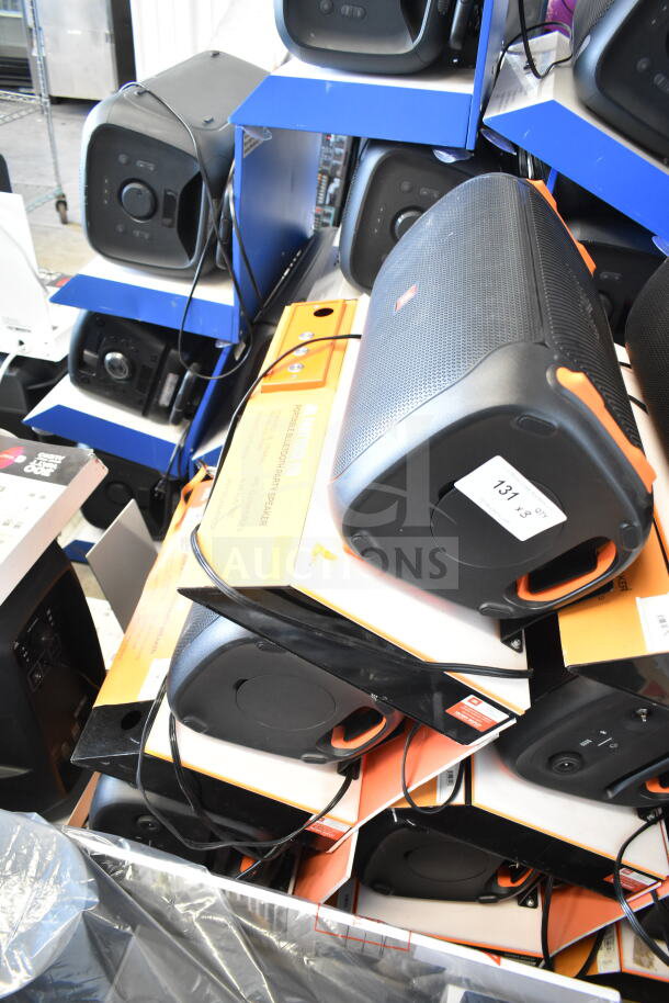3 JBL speakers in a store display, featuring Bluetooth capability. Black with orange accents, new in box. Quantity tag visible.
