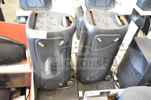 Two JBL Partybox 310 speakers on store display, lightly used. Visible control panels and branding. Marked "137" and "134".