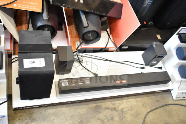 LG sound bar and 4 speakers display, model S55TR. Includes power cords, minor wear. Store tag: "138 QTY 1."