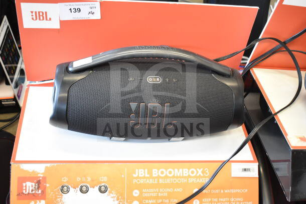 JBL Boombox 3 speaker on display stand, featuring massive sound, waterproof, with original packaging. Condition appears good.