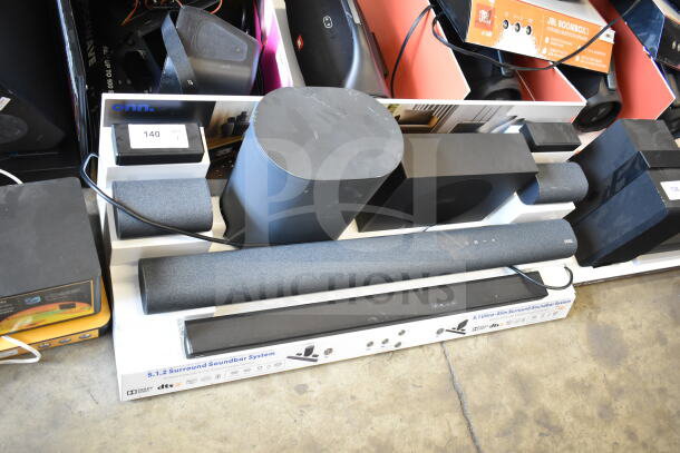 Store display featuring 2 soundbars and speakers, labeled with brand logos and specifications. Good condition.