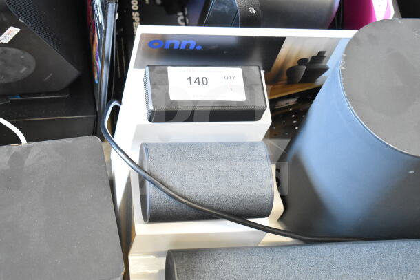 Store display featuring two ONN soundbars and speakers, in new condition. Marked with "140" and "QTY 1" tag.