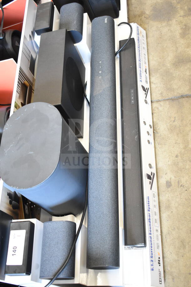 Store display with two soundbars, multiple speakers, and subwoofers. Features sleek design, visible "dts:X" label. Model info and condition not specified.