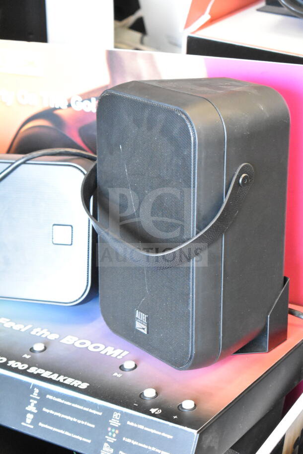 Altec Lansing Shockwave speaker on store display, featuring black casing and strap. Visible promotional text and product details.