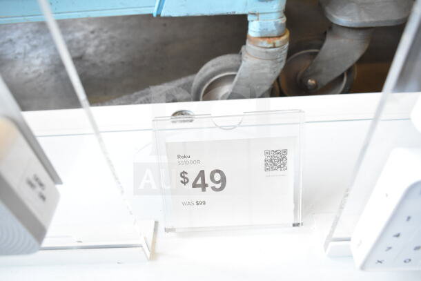 Store display sign for Roku SS1000R camera showing price drop from $99 to $49, includes QR code for details.