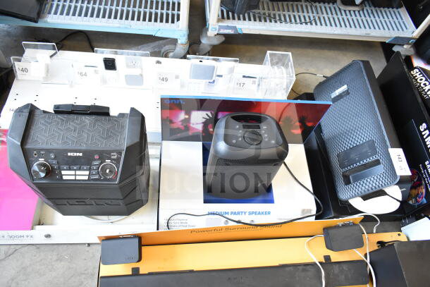 Three store display speakers: Ion speaker with control panel, Onn medium party speaker, and textured Samsung speaker.