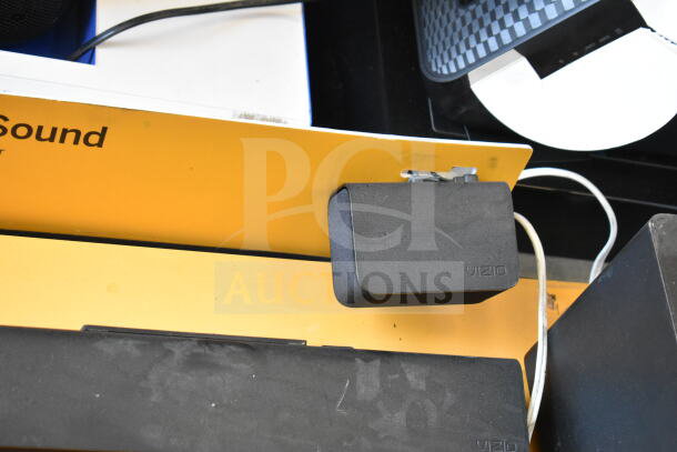 Store display featuring a Vizio sound bar and speaker in used condition. Vizio branding visible, with wiring attached.
