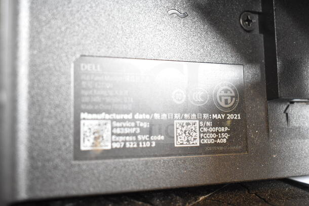 Close-up of a Dell monitor label, showing manufacturing date May 2021 and serial number details.