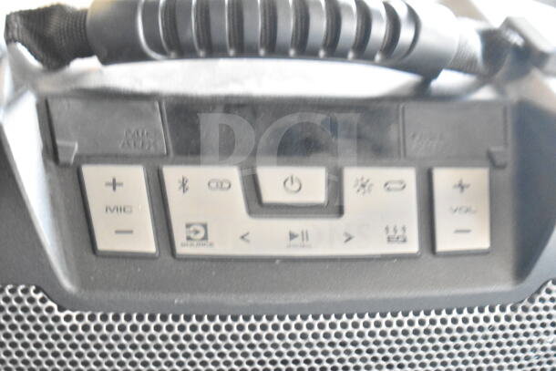 Ion speaker close-up, featuring control panel with power, volume, and Bluetooth buttons. Black handle, mesh grille. Good condition.