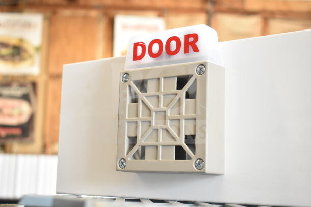 Emergency sign labeled "DOOR," white with red text, mounted on a beige speaker box. Appears in good condition.