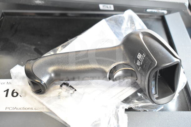 Barcode scanner in new condition, black plastic, shown with packaging materials, part of a 6-item auction lot.