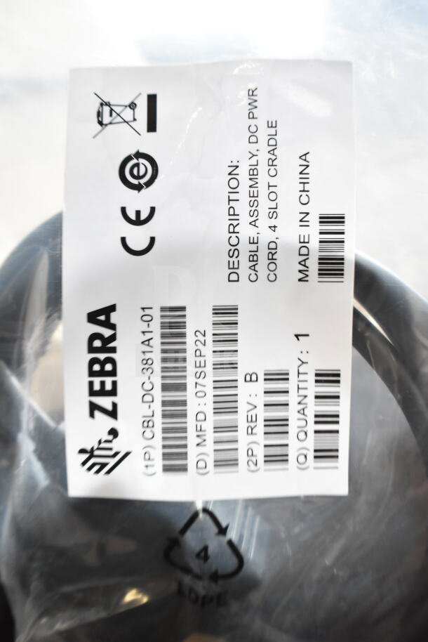 Zebra CBL-DC-381A1-01 cable in packaging. Label indicates "Cable Assembly, DC PWR Cord, 4 Slot Cradle," made in China.