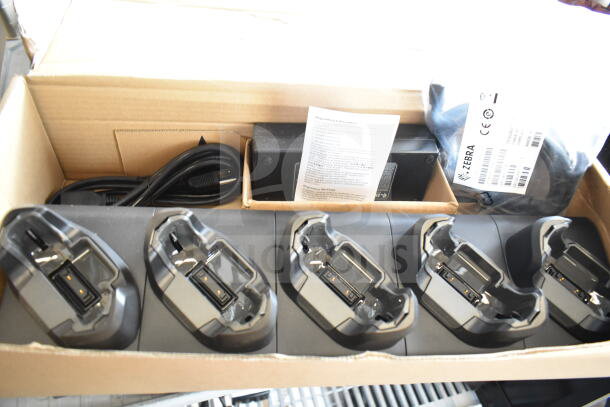 6 items including Hart CGH006 battery charger, barcode scanner, UCL172-4 quad charger in original packaging. Items appear unused. Labels show product details.
