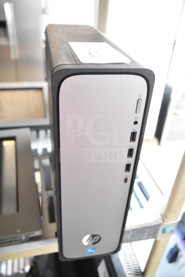 HP computer tower in silver, features USB ports and power button. Visible HP logo. Good condition.