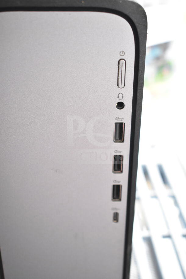 HP computer tower with power button, headphone jack, and three USB ports visible. Silver and black casing.