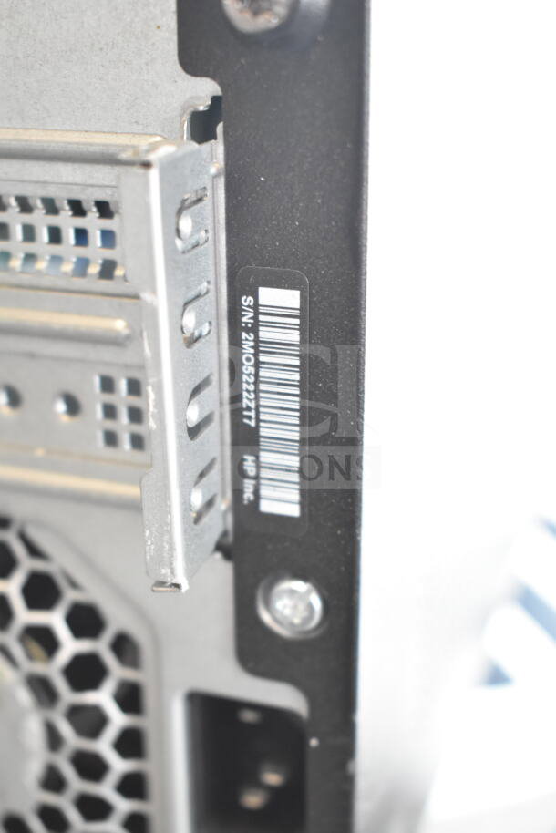 HP computer tower with rear view showing serial number 2MO5222T7. Features include vented metal panel.