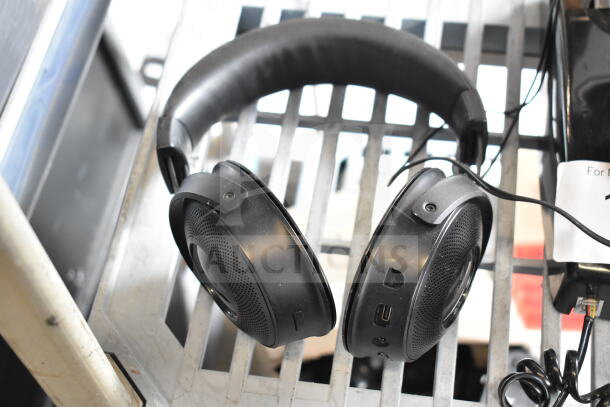 Four items including three black headphones and a telephone. Headphones show ports and buttons. Suitable for music lovers.