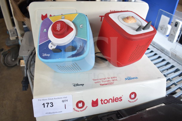 Store display with blue Disney Toniebox and red Toniebox on branded stand; features controls and illustration.