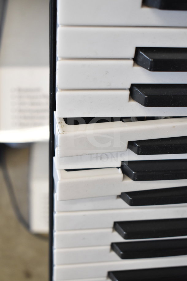Close-up of a white and black keyboard, showing damaged and misaligned keys. Signs of wear and tear are visible.