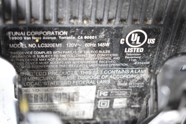 Close-up of Funai monitor label, model LC320EM1, indicating 120V, 60Hz, 145W; FCC compliant, UL listed.