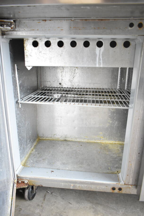Continental SW48N12M sandwich prep table interior, stainless steel, commercial casters, shows light wear and residue.