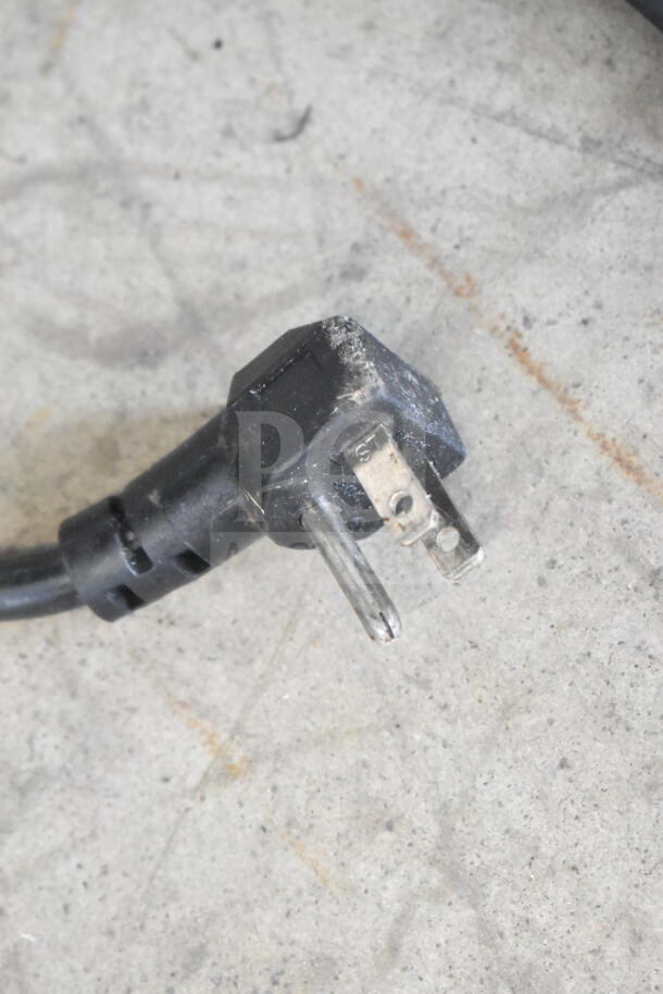 A close-up of a power plug for the Continental SW48N12M salad prep table, showing some wear on a concrete floor.