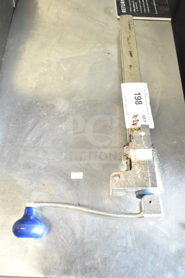 Commercial can opener with a blue handle, mounted on a metal surface. Visible label reads "198." Some wear on the opener.