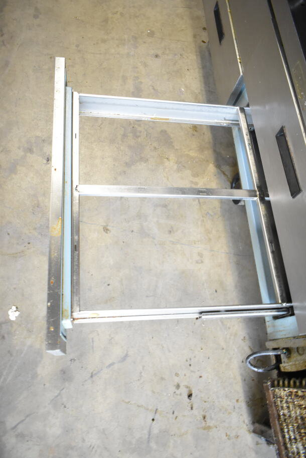 Delfield commercial 4-drawer chef base on casters, 115V, 1 phase, partial view, shows metal drawer frame and casters.