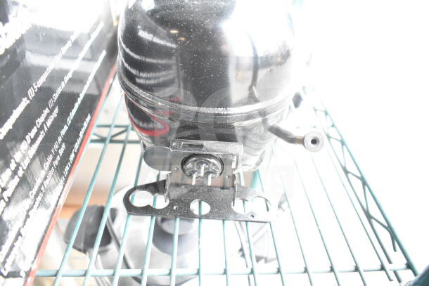 BRAND NEW SCRATCH AND DENT Embraco EM2X3125U Avantco 17812325 Compressor, 115-127 Volts, 1 Phase, shown on shelf.