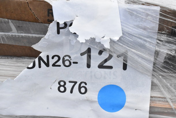 Auction item label showing "JUN26-121" and part of the packaging for new scratch and dent items, including a shelf and work table.