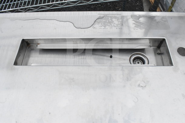 Commercial soda station with missing drip tray grate, stainless steel surface, visible drainage hole and signs of wear.