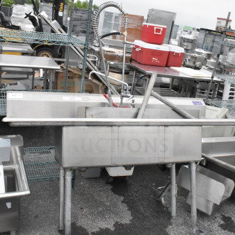 Commercial 3 bay stainless steel sink with dual drain boards, faucet, and spray nozzle attachment; used condition.