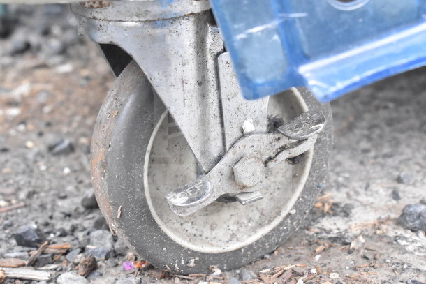 Poly Portable Ice Bin on commercial caster wheel, showing braking mechanism, moderate wear, suitable for mobility.