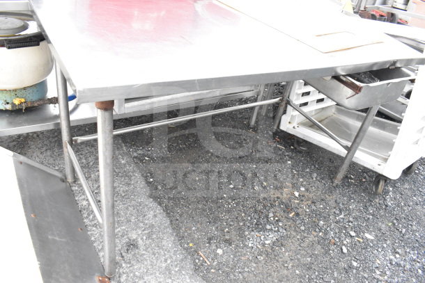 Commercial stainless steel table with drawer, sturdy metal legs, slightly worn condition, ideal for kitchen use.