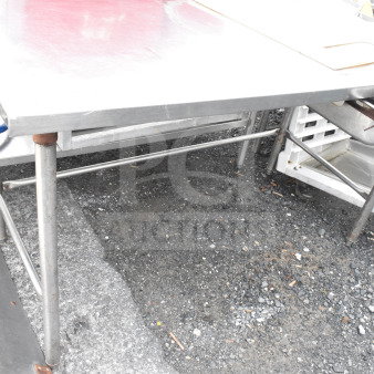 Commercial stainless steel table with drawer, sturdy metal legs, slightly worn condition, ideal for kitchen use.