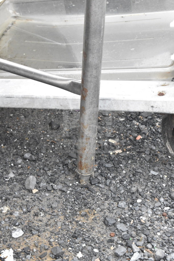 Commercial table with drawer, metal construction, showing signs of rust on legs. Suitable for industrial use.