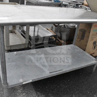 Commercial stainless steel table with under shelf, showing wear, ideal for food service use.