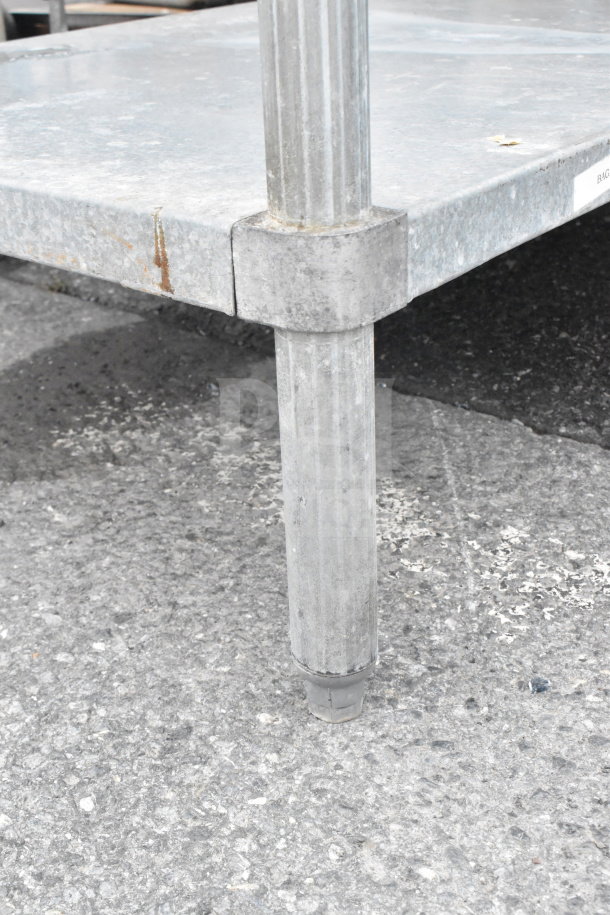 Commercial metal table with under shelf, showing sturdy legs and slight wear, ideal for industrial use.