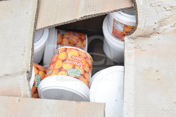 Pallet of numerous Del Monte apricot jam buckets within cardboard box; visible packaging includes "Del Monte" logo and product label.