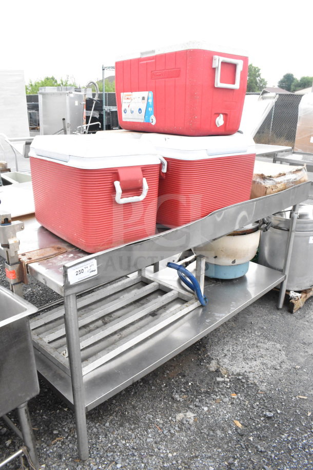 Commercial table with red portable coolers, stainless steel dunnage rack, and a rice cooker; visible wear.