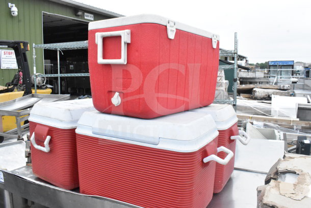Commercial table with red portable coolers, a dunnage rack, and rice cooker. Coolers have white lids and handles.