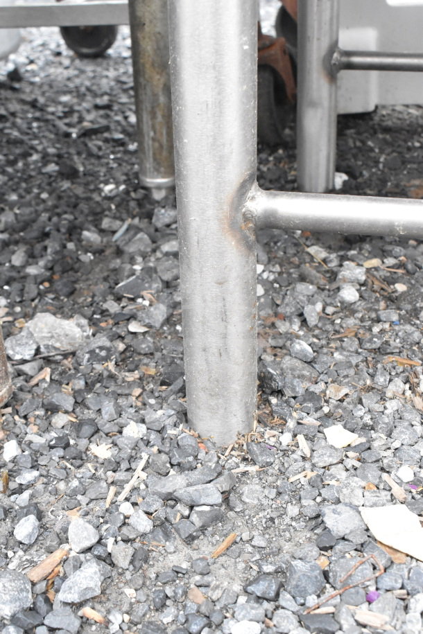 Commercial single bay ice bin, metal construction, holding baking pans, located outdoors on gravel surface.