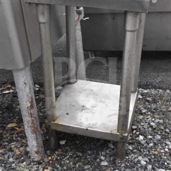 Commercial steel table with under shelf, worn condition; ideal for heavy-duty kitchen use. Rust visible on base legs.