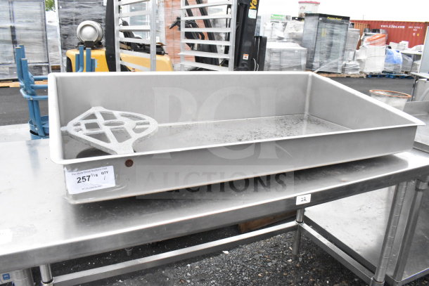 Commercial meat grinder tray on stainless steel table, showing robust construction. Visible minor wear, label "257" attached.