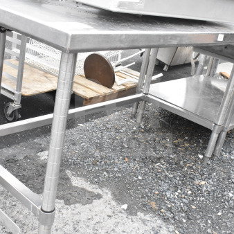 Stainless steel commercial table with adjustable legs, featuring a lower shelf. Used condition with minor surface wear.